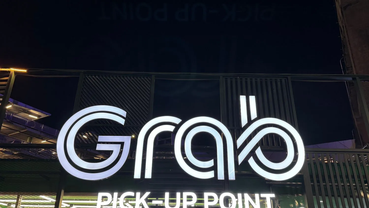 Illuminated Grab pick-up point sign at a Bangkok airport at night