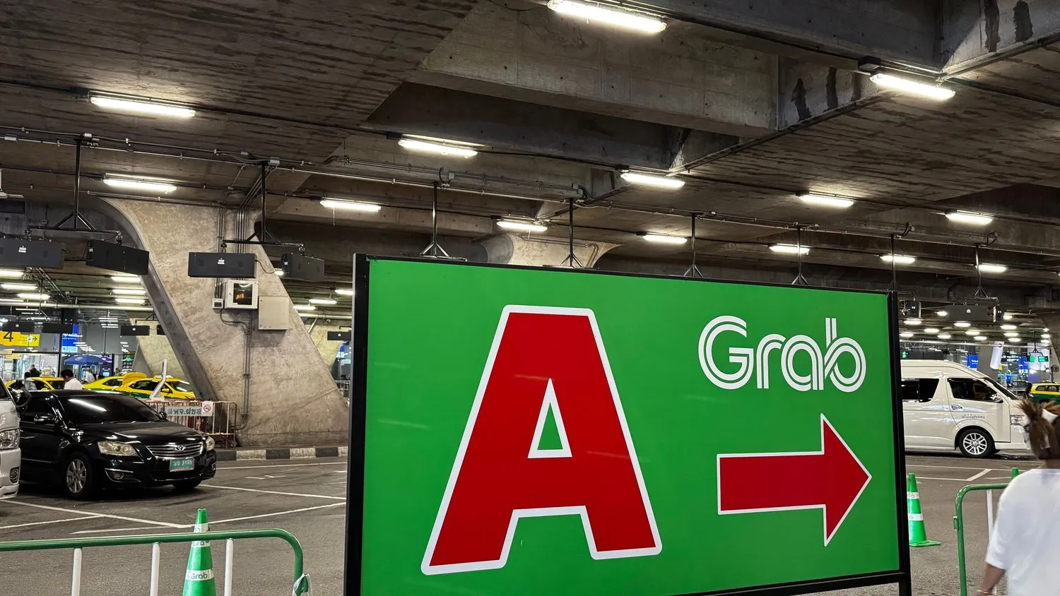 Ground-transport pickup zones beneath Suvarnabhumi airport, with taxis and a Grab zone sign
