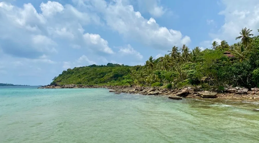A rocky turquoise bay fringed with palms on Thailand's coast